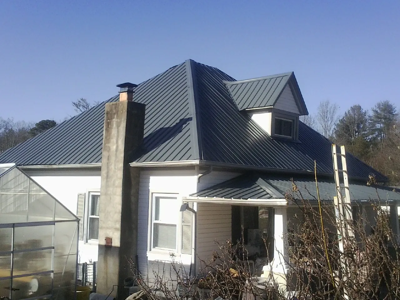 Dark blue standing seam metal roof on a white farmhouse with dormer — Slate & Tile Roof Repair by Roofing Brothers in Harleysville