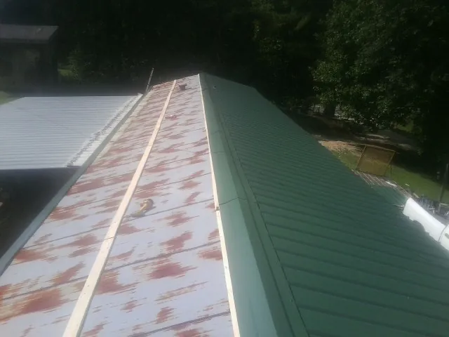 Old rusted panels beside newly installed green metal roofing — Wind Damage Roof Repair by Roofing Brothers in Harleysville