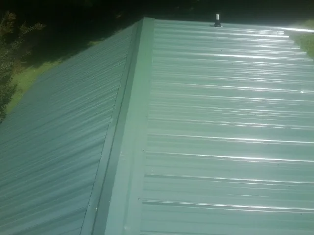 New green metal panels meeting at the ridge of a roof — Flat Roof Repair work by our crew in Harleysville