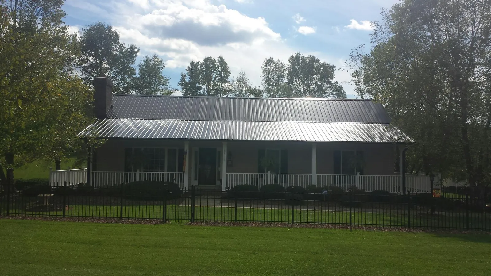 Gray metal roof on a brick ranch with a full width front porch — Gutter Guard Installation work by our crew in Harleysville