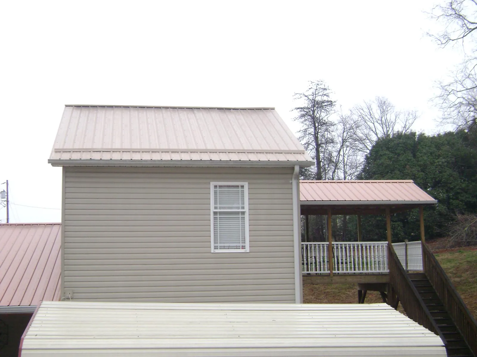 Tan metal roofs on a two story addition and attached porch, from a Roof Replacement job in Harleysville