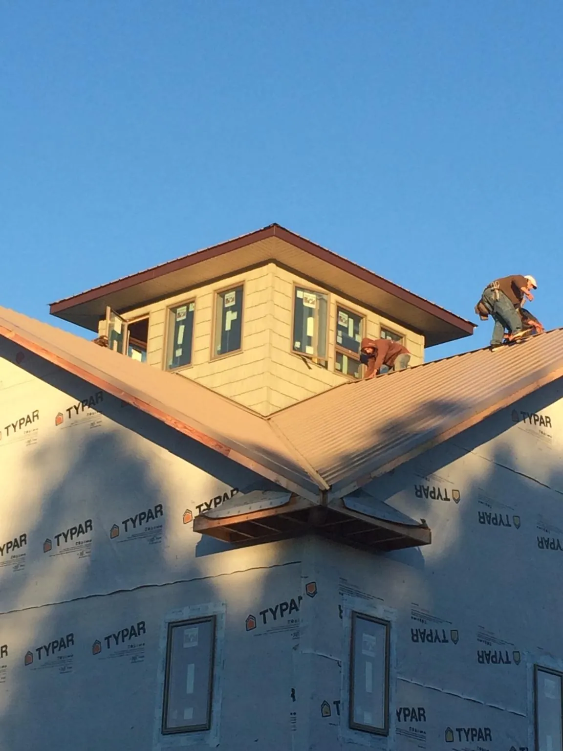 Roofers working around a rooftop cupola on a new metal roof at sunset — Roof Waterproofing in Harleysville by Roofing Brothers